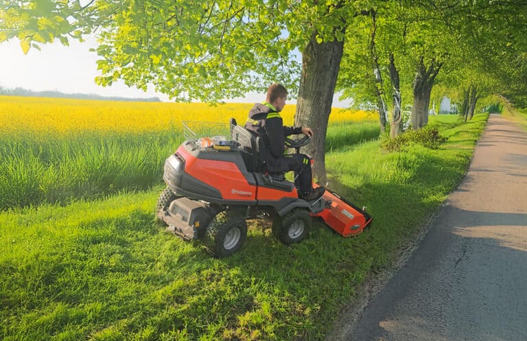 Mowing grass along the roadside using professional equipment.