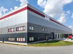 Exterior view of the WELL PACK warehouse in Mstětice (Prague-East) with loading docks and parking area.