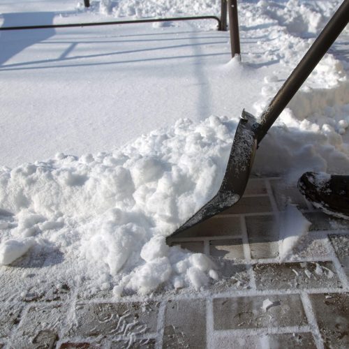 A man clears snow from a path after a blizzard using a snow shovel.