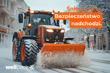 Traktor z pomarańczowym pługiem odśnieża ulice w centrum miasta – zimowe utrzymanie Wellpack